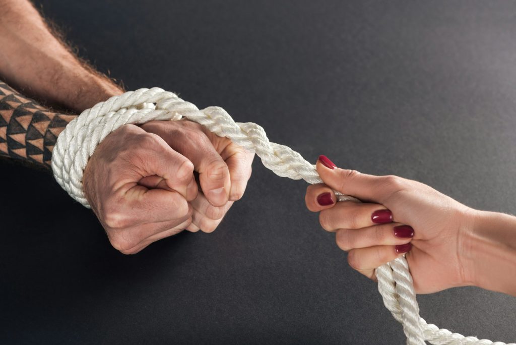 cropped view of woman holding rope on male hands on black background