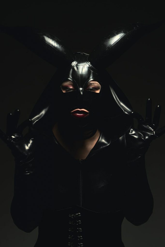 Histoire d’une dominatrice uro en latex : Madame Vesper Dark and moody studio portrait of a woman in a leather costume with horns.