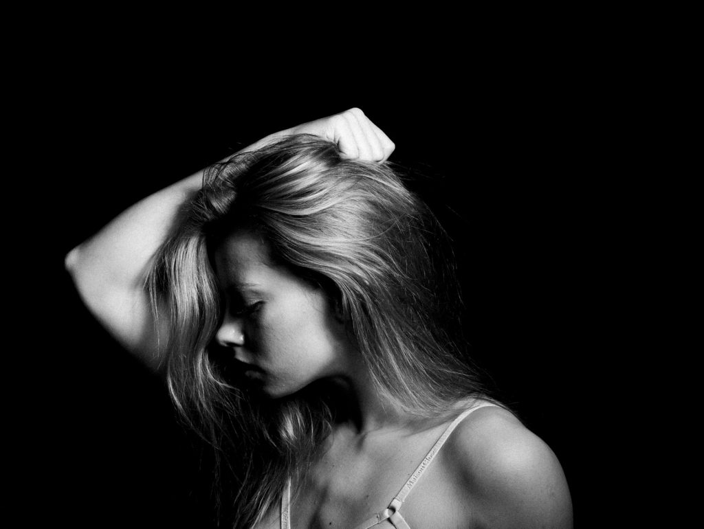 a black and white photo of a woman with her hand on her head